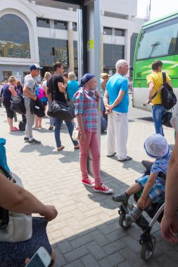 Krasnodar, Rusya Federasyonu - 27 Temmuz 2016-pembe pantolon içinde şık hipster kızla otobüs otobüs durağında bekleyen diğer insanların elinde bir iphone