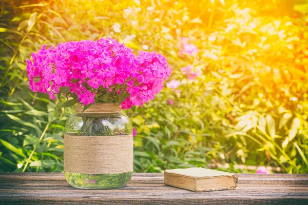 Nature morte d'été de bouquet de fleurs Phlox et petits livres anciens sur table en bois sur fond naturel ensoleillé, photo teintée — Photo