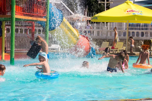 Gelendzhik, Rusia - 30 de julio de 2016 - Niños felices divirtiéndose en la piscina del parque acuático con salpicaduras de agua — Foto de Stock