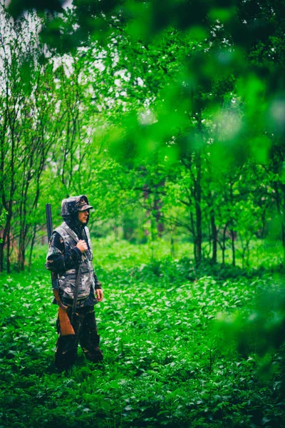 Hombre cazador con un arma camina en tiempo lluvioso en el bosque de primavera, foto teñida —  Fotos de Stock