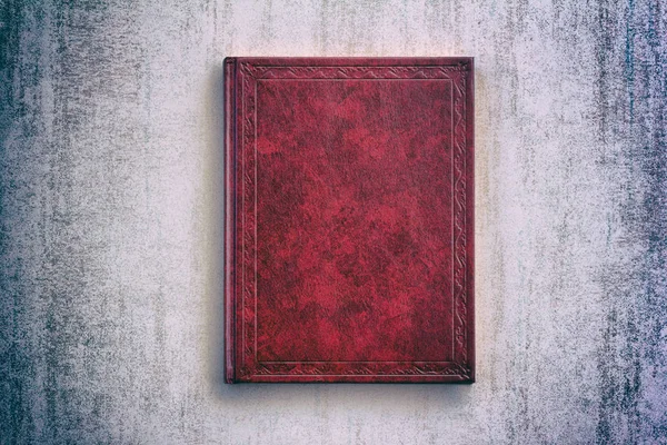 The book in a red cover over gray grunge background, top view with vignette — Stock Photo, Image