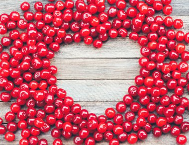 kalp sembol yapılmış ahşap arka plan üzerinde kiraz meyveleri, metin için yer ile Üstten Görünüm