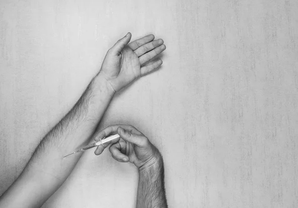 Las manos del hombre haciéndose una inyección de una jeringa médica desechable sobre un fondo gris con espacio para el texto. foto en blanco y negro — Foto de Stock