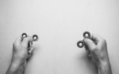 erkekler elleriyle popüler spinner oyuncak metin üstten görünüm, siyah ve beyaz fotoğraf yeri olan gri bir arka plan üzerinde kıpır. Dalga metin, ifadeler, yazı için