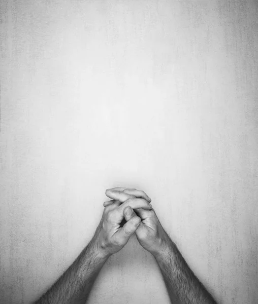 Manos de un hombre se pliegan en una cerradura sobre un fondo gris, vista superior. foto en blanco y negro, maqueta de texto, frases, letras — Foto de Stock