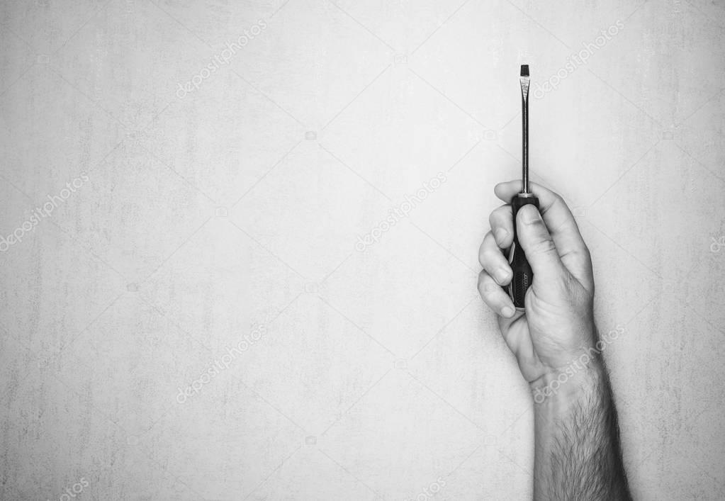 Screwdriver in a man's hand on a gray background, top view. black and white photo. mock up for text, phrases, lettering