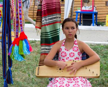 sad girl playing music on the harp at the festival of cheese Adyghe in Adygea clipart