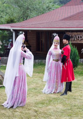 güzel genç kız ve bir erkek bir cep telefonuna peynir Adıge Çerkezce Festivali'nde geleneksel Çerkes kostümleri fotoğrafı
