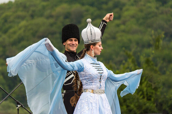 a beautiful young girl and a guy in a traditional Circassian costumes dance at the open Adyghe cheese festival in Adygea