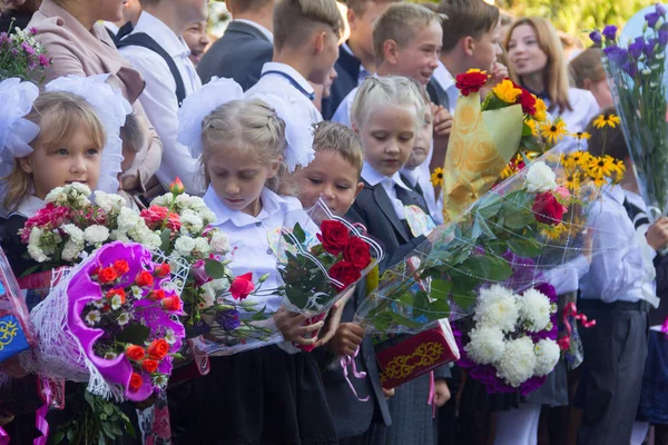 Niños con ramos de flores matriculados en primer grado con estudiantes de secundaria en la escuela la regla solemne en el día del conocimiento — Foto de Stock