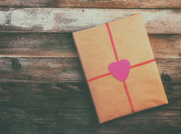 Kağıt ambalaj Sevgililer günü hediyesi kırmızı kurdele ile metin, üstten görünüm yakın kadar renkli fotoğraf için yer ile ahşap vintage grunge arka plan üzerinde bir kalp ile bağlı — Stok fotoğraf