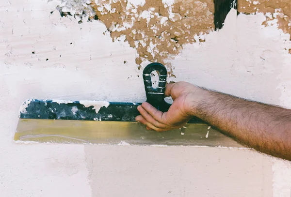 Волосатый ручной гастарбайтер со стальной лопаткой, оштукатурирующей стену — стоковое фото