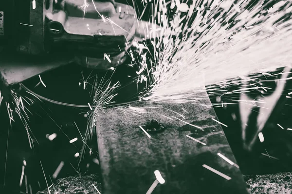 Chispas que vuelan desde debajo de la amoladora de disco giratorio al limpiar piezas de acero después de la soldadura, imagen en blanco y negro — Foto de Stock