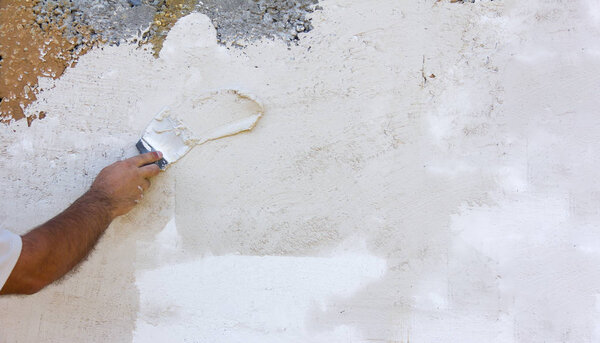 background texture white rough plastered walls and a male hand with a spatula. mock up for text, phrases, lettering