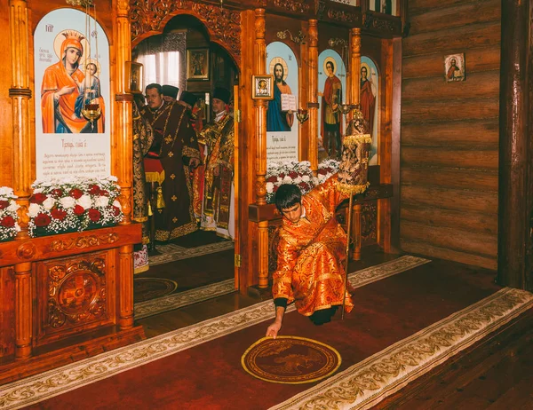De jongeman subdiaken rechtmaakt de deken voor het altaar in een orthodoxe kerk van de Goddelijke Liturgie — Stockfoto