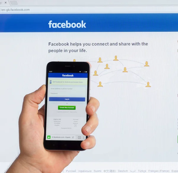Adıge, Rusya - 5 Ocak 2018: En büyük Amerikan sosyal ağı Facebook Çin telefonu Xiaomi erkek elinde ekranında ve bilgisayar monitör