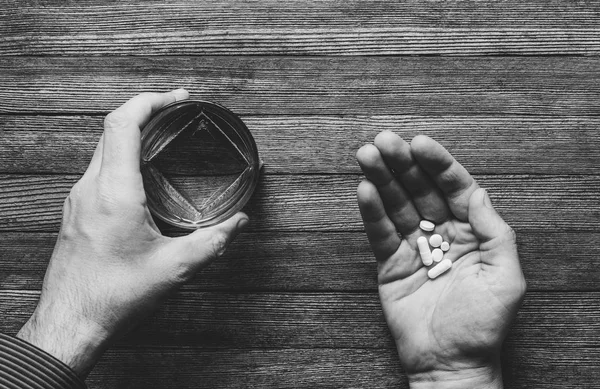 the man is going to eat pills and capsules and taken with water, black white photos top view