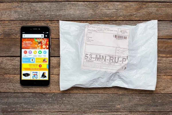 Adıge, Rusya - 24 Ocak 2018: Çin online mağaza mobil uygulama ali hızlı üstünde belgili tanımlık perde smartphone xiaomi ve paket parsel üzerinde ahşap masa