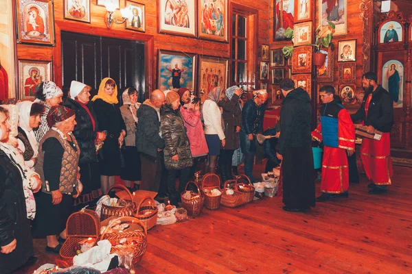 正統派の司祭が木造の教会でイースター ケーキと卵と聖なる水をはぐくみ Adygea ロシア 2015 — ストック写真