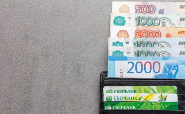 Adıge, Rusya - 10 Şubat 2018: Rus banknotlar, 1000, 2000 ve 5000 ruble ve kredi kartları Sberbank kopya alanı ile gri bir arka plan üzerinde siyah deri çanta yakın banknottan