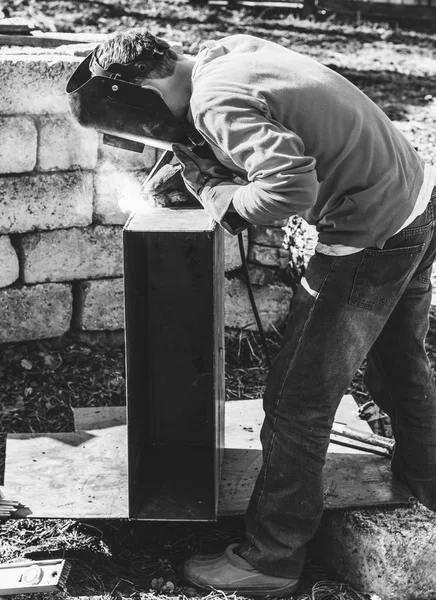 a welder puts the seam on the metal electro arc welding, black and white photo