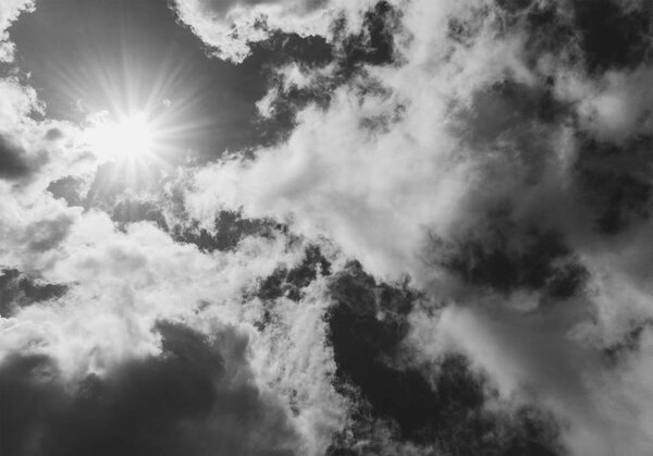 Bright sun is closed by clouds, black and white photo