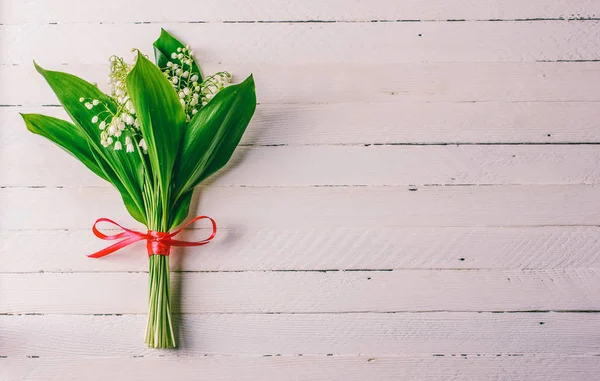 コピー スペースと白い木製の背景に赤いリボンで結ばれたユリの花の花束 — ストック写真