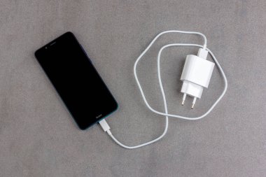 Krasnodar, Rusya - 23 Kasım 2019: Çinli akıllı telefon Xiaomi Redmi 7a Gem Blue ile siyah ekran ve beyaz şarj cihazı ile arka planda yakın plan görüntüsü