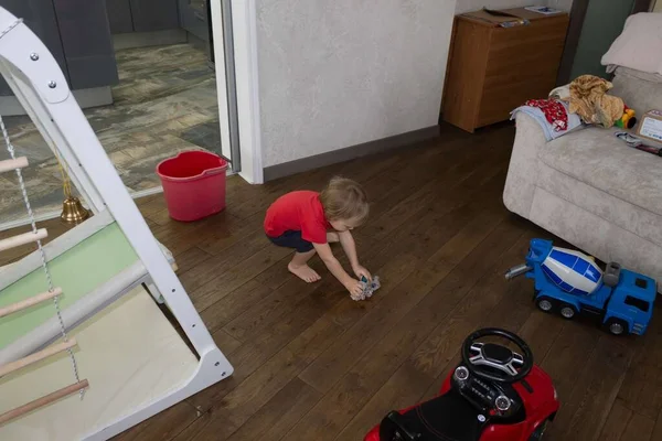 a small child washes the floors in the room with a wet rag, the concept of helping parents and child labor