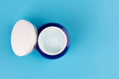 Mavi kavanoz ve ışık günü nemlendirici hyaluronik krem jeli mavi arka planda fotokopi alanı manzaralı.