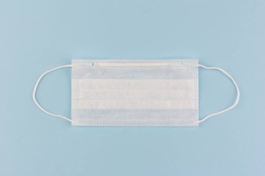Mavi arka planda tek kullanımlık tıbbi maske, Coronavirus COVIND-19 salgını sırasında tıbbi maske kıtlığı.