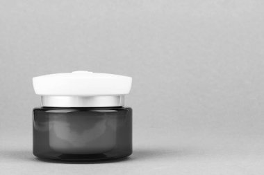 Işık dolu bir kavanoz. Hyaluronik krem jöleyi nemlendiriyor. Gri arka planda fotokopi alanı olan bir yüz için.