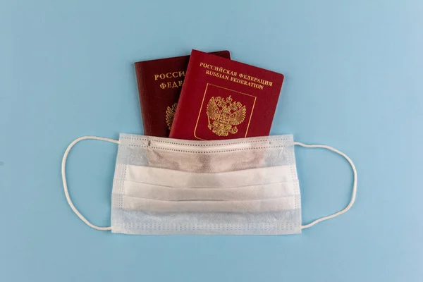 Dwa Rosyjskie Paszporty Pod Jednorazową Maską Medyczną Niebieskim Tle Widok — Zdjęcie stockowe