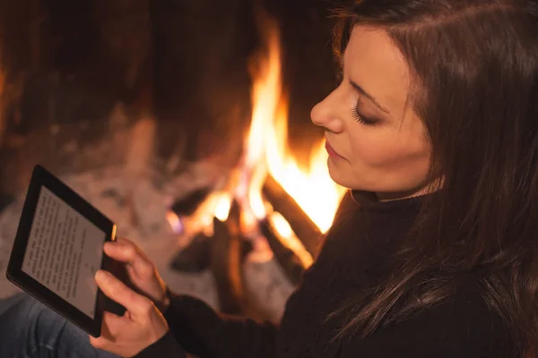 Bella donna che legge ebook seduto vicino al focolare — Foto Stock