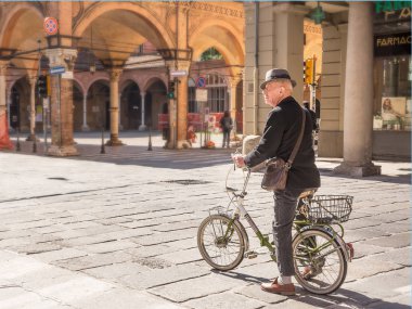 Senior bicycle man in the center of bologna in a sunny day clipart