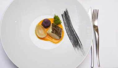 Morina balığı üzerinde krem biber ve soğan parçası