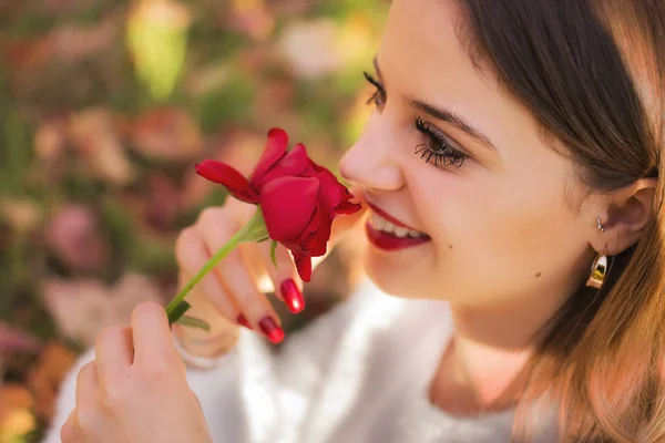 女孩嗅到一朵红玫瑰 — 图库照片