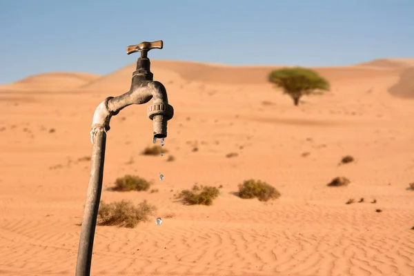 Druppelende kraan en woestijn milieu op de achtergrond — Stockfoto