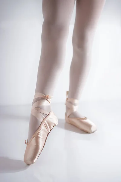 Benen en voeten met roze satijnen puntschoenen van een klassieke danser — Stockfoto
