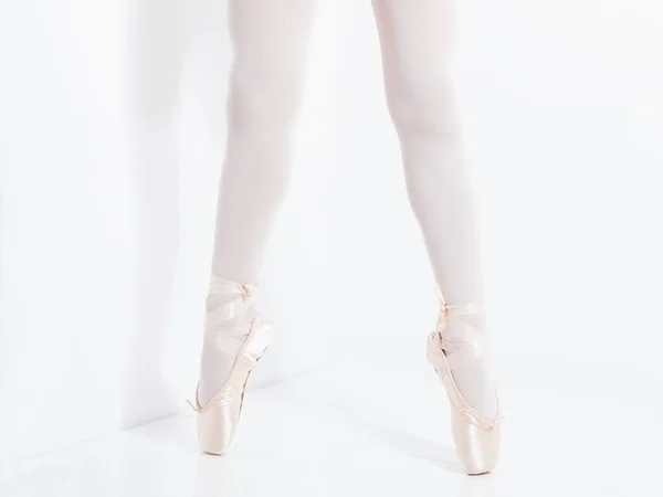 Benen en voeten met roze satijnen puntschoenen van een klassieke ballerine — Stockfoto