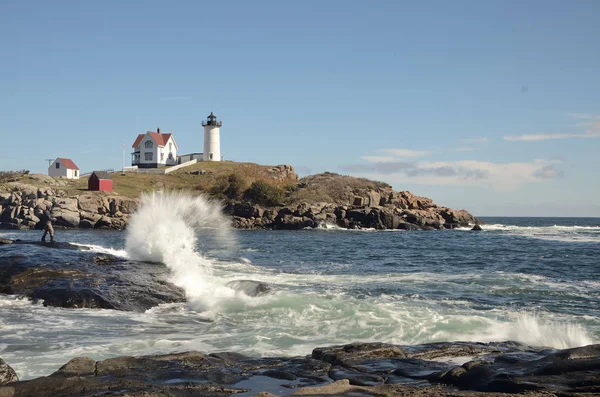 Waves crashing in front of Nubble lighthouse, Cape Neddick Maine. Blue sky