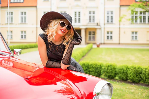 Mujer con sombrero de lujo y gafas de sol con coche retro — Foto de Stock