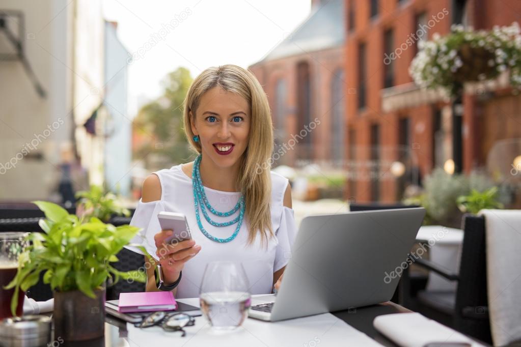 Happy business woman with laptop and smartphone
