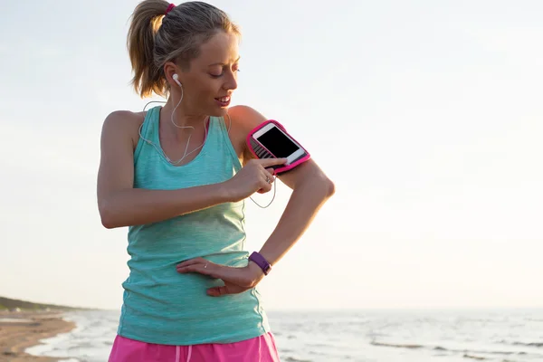 Жінка перемикає пісні на свій мобільний телефон під час тренування — стокове фото