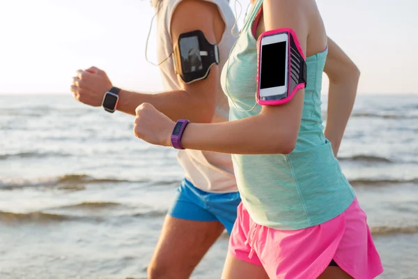 Couple running on the beach with their mp3 players — Stock Photo, Image