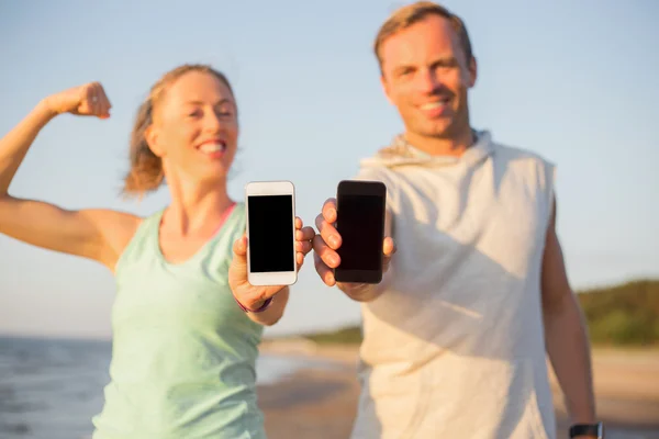 Feliz e apto casal segurando seus smartphones — Fotografia de Stock