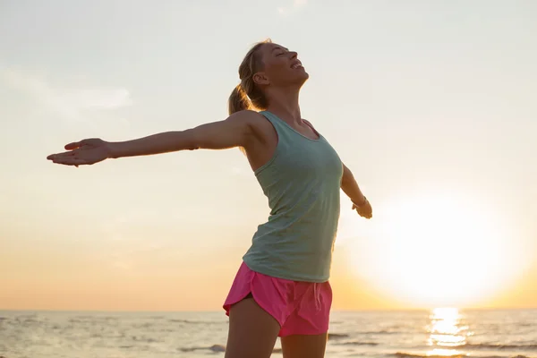 Gelukkig en fit vrouw mediteren op het strand — Stockfoto