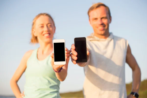 Pelari di pantai memegang smartphone mereka — Stok Foto