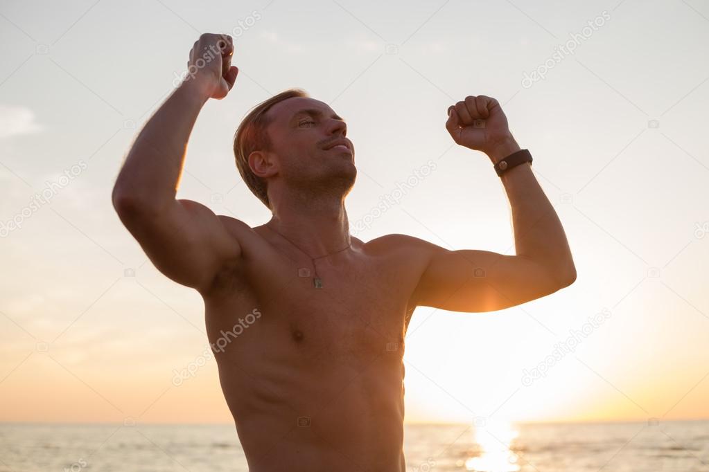 Happy man after workout standing in the sunset