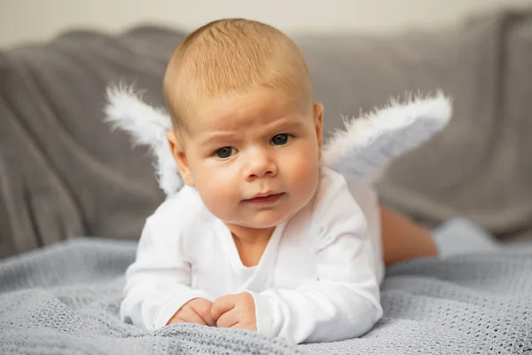 Baby om på magen med änglavingar fäst — Stockfoto